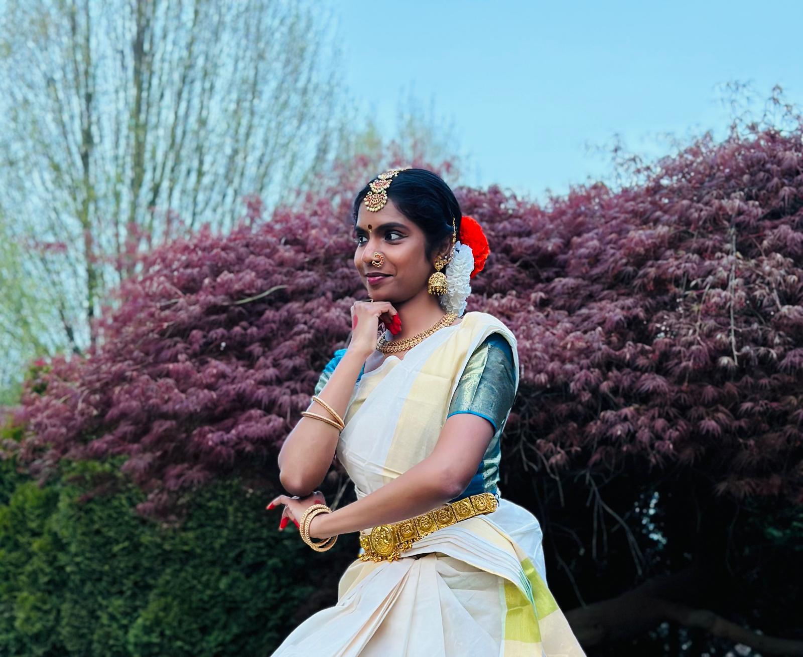 Amulya Keshoju poses outside - they are wearing traditional Kuchipudi outfit, hair pieces and jewelry.